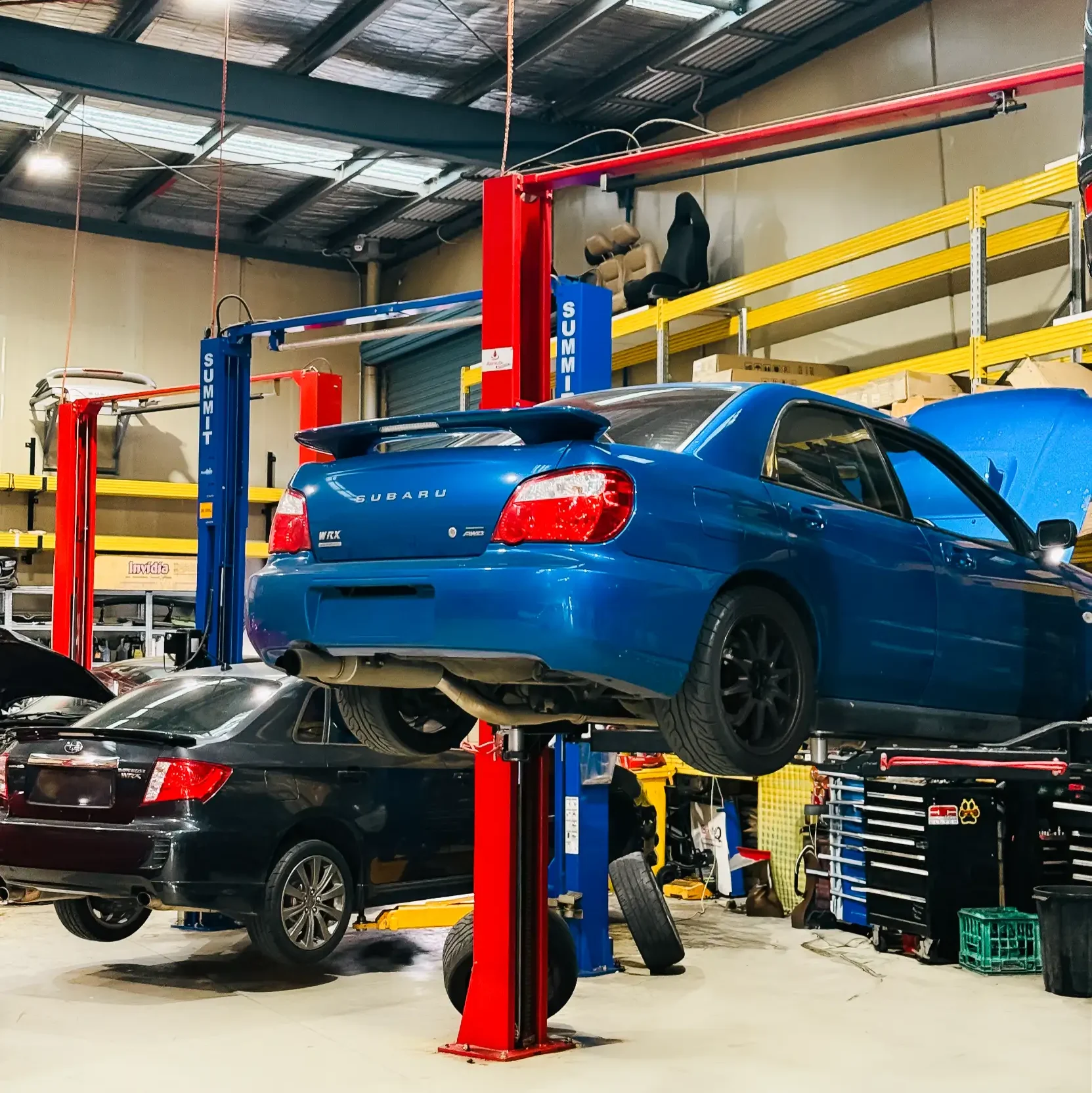 Blue Subaru WRX raised on a hoist inside Garage Full Throttle's Craigieburn workshop for a full undercarriage inspection, checking common roadworthy failure points.