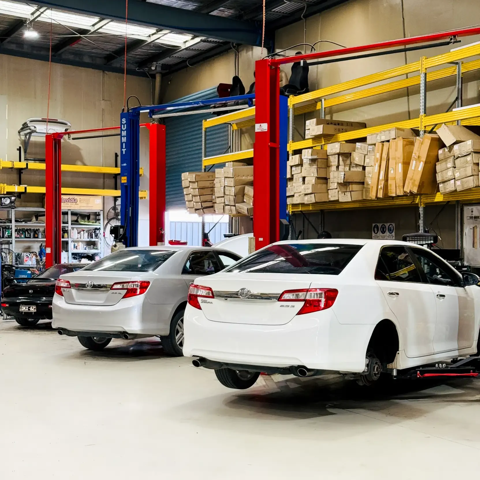 Multiple vehicles lined up inside Garage Full Throttle's Craigieburn workshop bays, ready for roadworthy inspections on a busy service day.