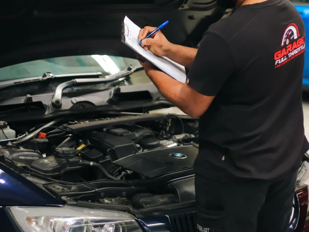 Mechanic using Paper Checklist to perform roadworthy inspection checklist inside vehicle bonnet