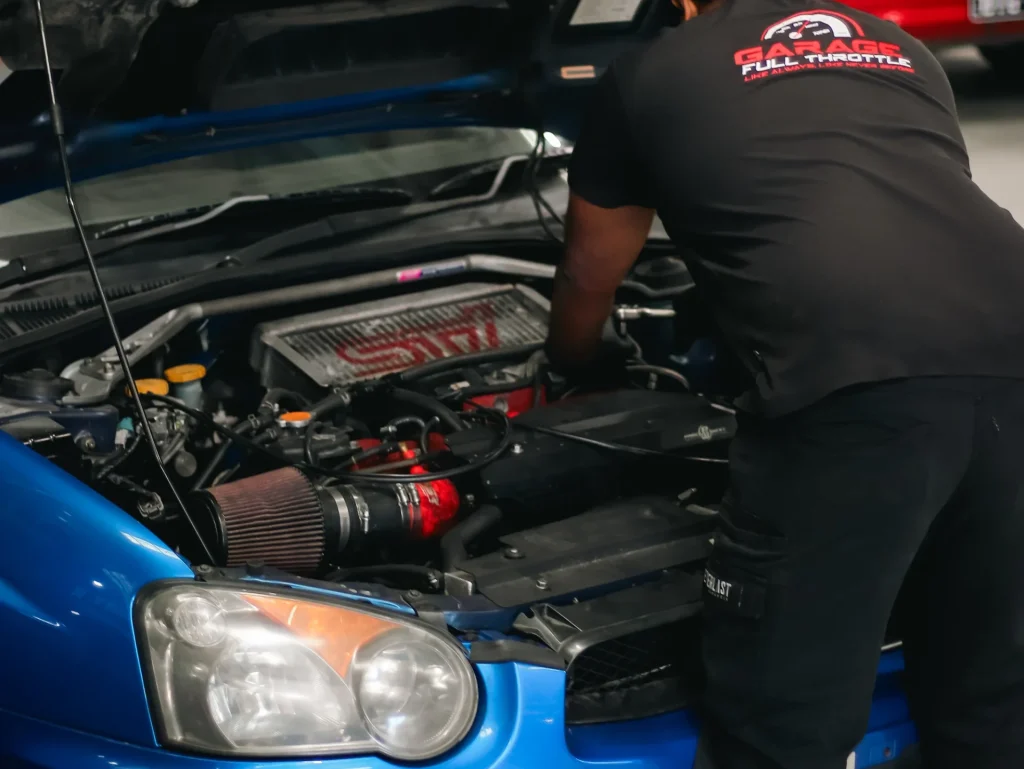 Garage Full Throttle mechanic performing professional roadworthy inspection on Subaru WRX engine bay